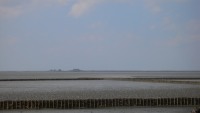 Op de horizon steken wat terpen boven het water uit. Dat is alles wat je ziet van Hallig Nordstrandischmoor.