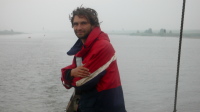 Walter staat aan het roer op weg naar de sluis van Greetsiel. Het is grauw weer, maar het belooft een mooie tocht te worden.